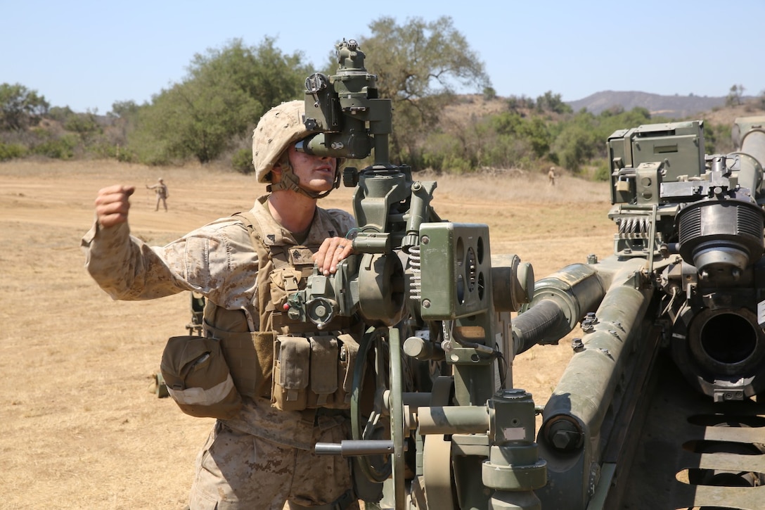 Corporal Bryan Rinell, field artillery cannoneer, India Battery, 1st Battalion, 11th Marine Regiment, signals to his fellow Marine where to place a howitzer's deflection posts during an annual, live-fire training exercise here, Aug. 23, 2013. Marines with the entire regiment conducted the live-fire training exercise from Aug. 19 through 28.