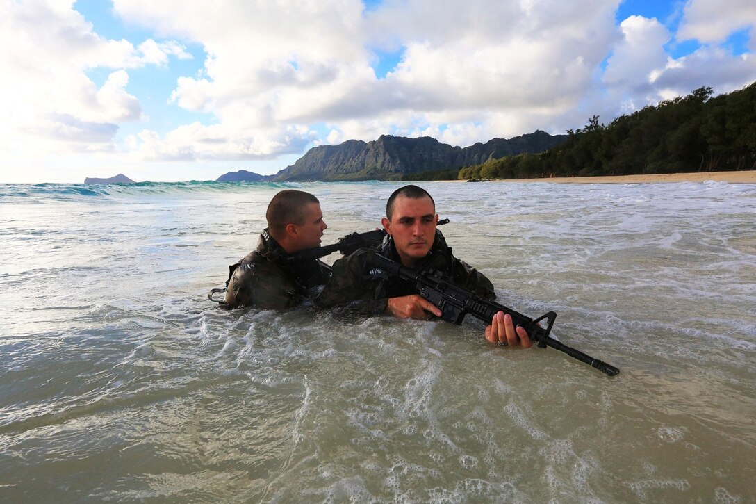 Two Reconnaissance Marines with Battalion Landing Team 1/4, 13th Marine Expeditionary Unit, wade ashore at Bellows Beach on the Island of Oahu, Hawaii, during sustainment training Aug. 31, 2013. The Marines left the USS Boxer on Combat Rubber Reconnaissance Craft (CRRC) just after sunrise with the objective of securing an area of Bellows Beach thus allowing Landing Craft Air Cushion’s (LCAC’s) to land and transport military vehicles ashore. The Marines and Sailors with 13th MEU will deploy for several months in support of theater requirements of Geographic Combatant Commanders.  (USMC Photo by SSgt. Matt Orr/Released)