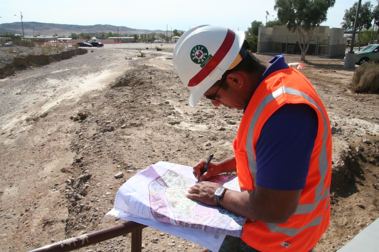 After a monsoon struck the Fort Irwin and the National Training Center, a five-man team from the U.S. Army Corps of Engineers Los Angeles District deployed to the Southern California base to conduct initial damage assessments.  Jose Rocha, a civil engineer, inspects a pedestrian bridge near the Mary Walker Clinic for damage and further use.  The raging waters and debris flow from the monsoonal rainfall eroded the soil and concrete around the bridges’ support footing. The bridge has been closed pending further analysis of the damage. (USACE photo by Brooks O. Hubbard IV)