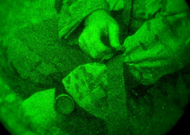 Staff Sgt. Craig Wheeler, 66th Rescue Squadron special missions aviator, applies a tourniquet to himself after a simulated aircraft crash during a survival, evasion, resistance, escape familiarization training Aug. 23, 2013, at Area 2, Nellis Air Force Base, Nev. The students each had a simulated wound they had to self-treat while under stressful conditions. (U.S. Air Force photo/Senior Airman Brett Clashman)