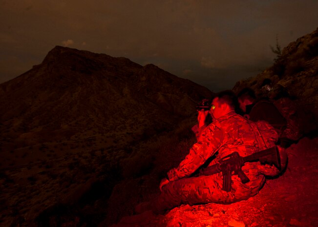 Staff Sgt. Craig Wheeler, 66th Rescue Squadron special missions aviator, analyzes the terrain with binoculars during a survival, evasion, resistance, escape familiarization training Aug. 23, 2013, at Area 2, Nellis Air Force Base, Nev. The training teaches students to understand what it takes to survive in a hostile environment while evading as an isolated unit. (U.S. Air Force photo/Senior Airman Brett Clashman)