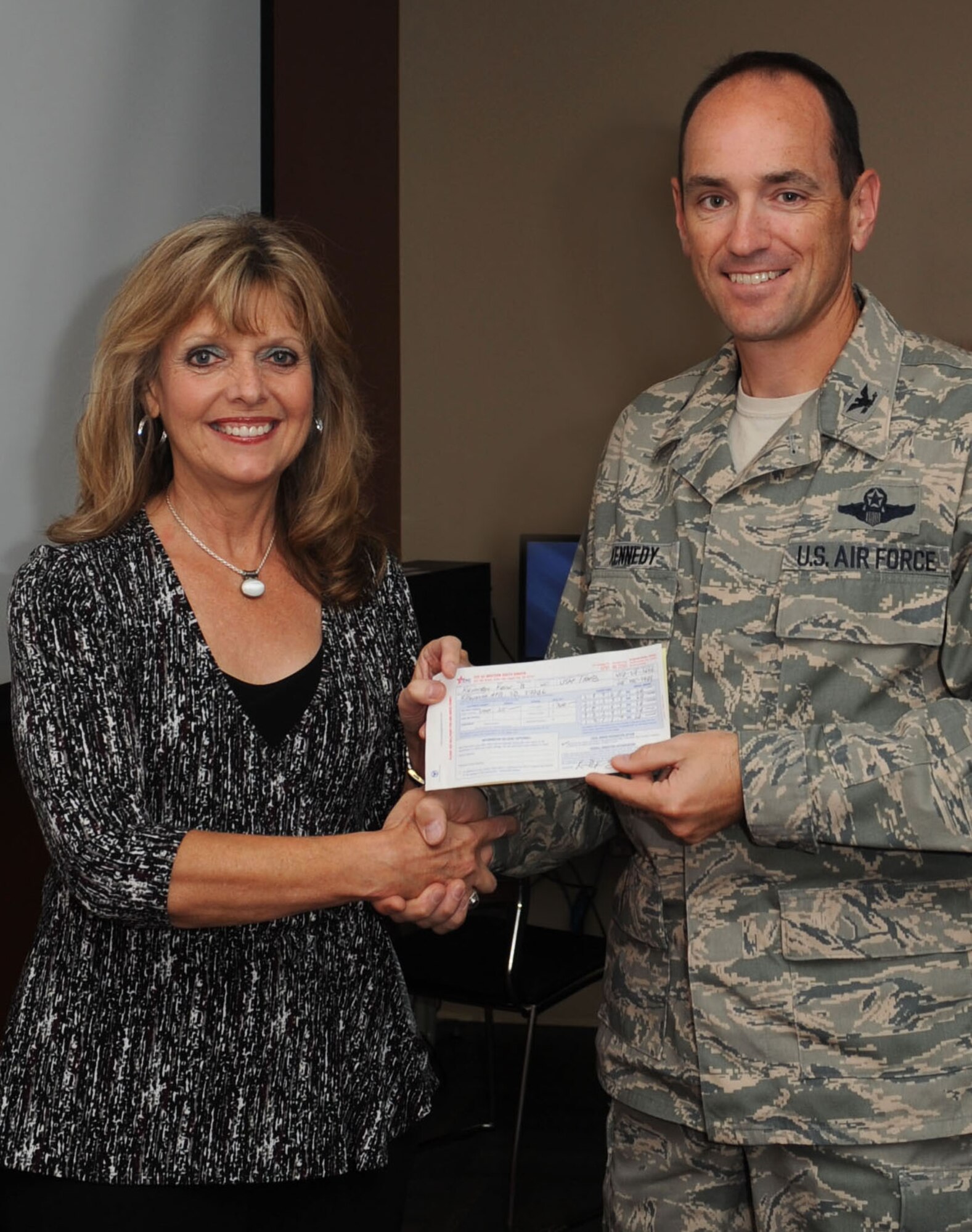 Col. Kevin Kennedy, 28th Bomb Wing commander (right), presents his completed Combined Federal Campaign pledge form to Renee Parker, United Way of the Black Hills executive director, during the CFC kickoff event at Ellsworth Air Force Base, S.D., Sept. 3, 2013. Those who donate have the choice to give to a specific local, national or international charity by filling out a donation form and giving it to their group or squadron representative. (U.S. Air Force photo by Airman 1st Class Rebecca Imwalle/Released)