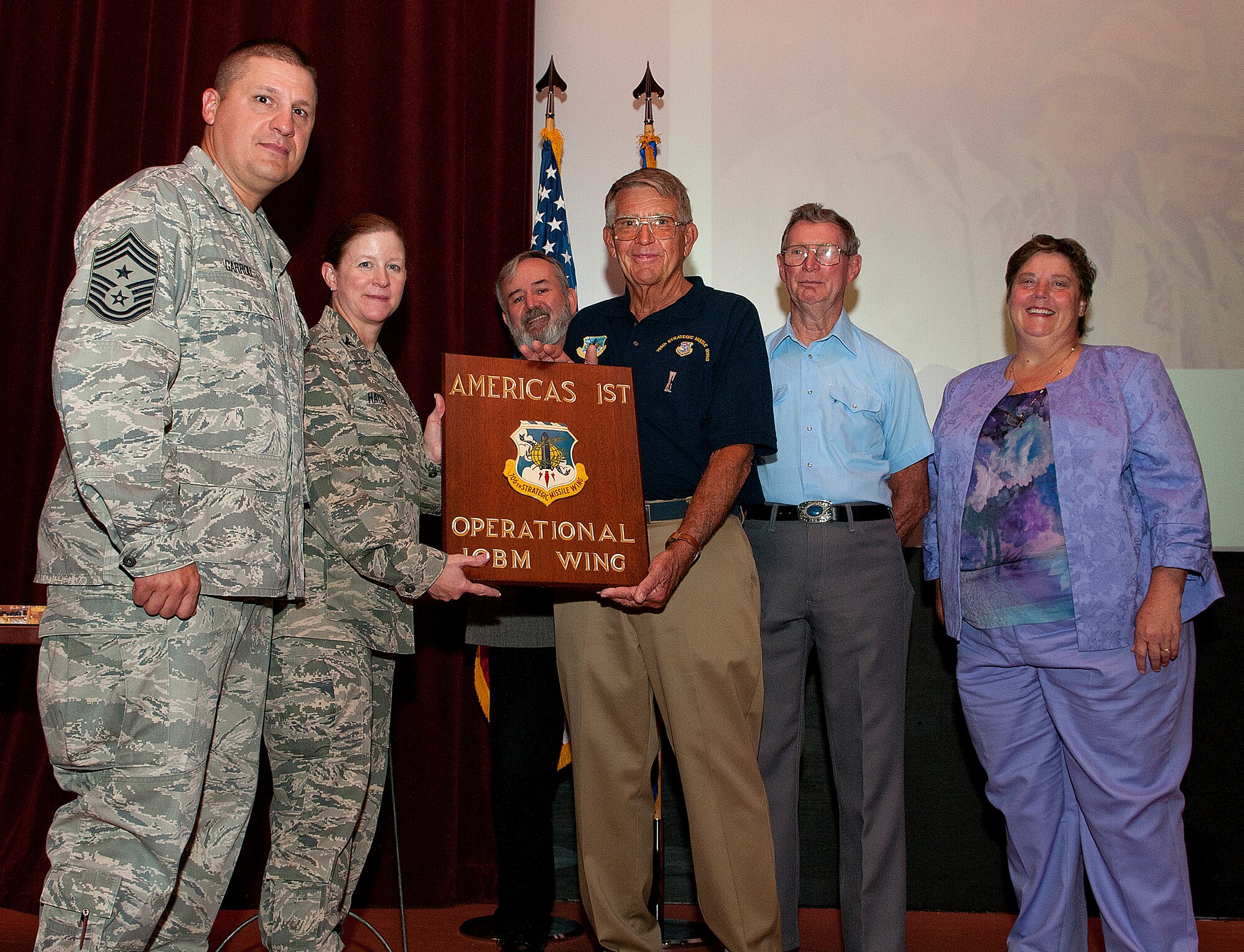 Jim Widlar and Frank Waters, former 706th Strategic Missile Wing members assigned here in the1950s and 1960s, presented to Col. Tracey Hayes, 90th Missile Wing commander; Chief Master Sgt. Mike Garrou, 90th Missile Wing Command Chief; Paula Taylor, 90th MW Museum curator; and Mike Byrd, 90th MW historian, the original Atlas missile plaque which states “706th Strategic Missile Wing, America’s 1st Operational ICBM Wing,” during a commander’s call in the Base Theater Aug. 27, 2013. The plaque was donated by Widlar and Waters to the base museum. (U.S. Air Force photo by R.J. Oriez)