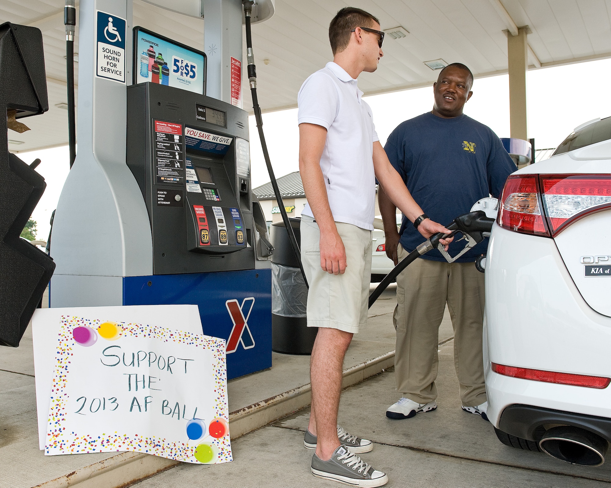 Airman 1st Class Warren Rehrer, center, 436th Contracting Squadron contracting specialist, pumps gas for Mr. Willie Hardy August 29, 2013, at the Dover Air Force Base, Del., Army and Air Force Exchange Service Express gas station/shoppette. Volunteers pumped gas for customers who donated money to the Company Grade Officers' Council sponsored pump-a-thon that raised donations for the 2013 Dover AFB Air Force Ball. (U.S. Air Force photo/Roland Balik)
