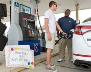 Airman 1st Class Warren Rehrer, center, 436th Contracting Squadron contracting specialist, pumps gas for Mr. Willie Hardy August 29, 2013, at the Dover Air Force Base, Del., Army and Air Force Exchange Service Express gas station/shoppette. Volunteers pumped gas for customers who donated money to the Company Grade Officers' Council sponsored pump-a-thon that raised donations for the 2013 Dover AFB Air Force Ball. (U.S. Air Force photo/Roland Balik)