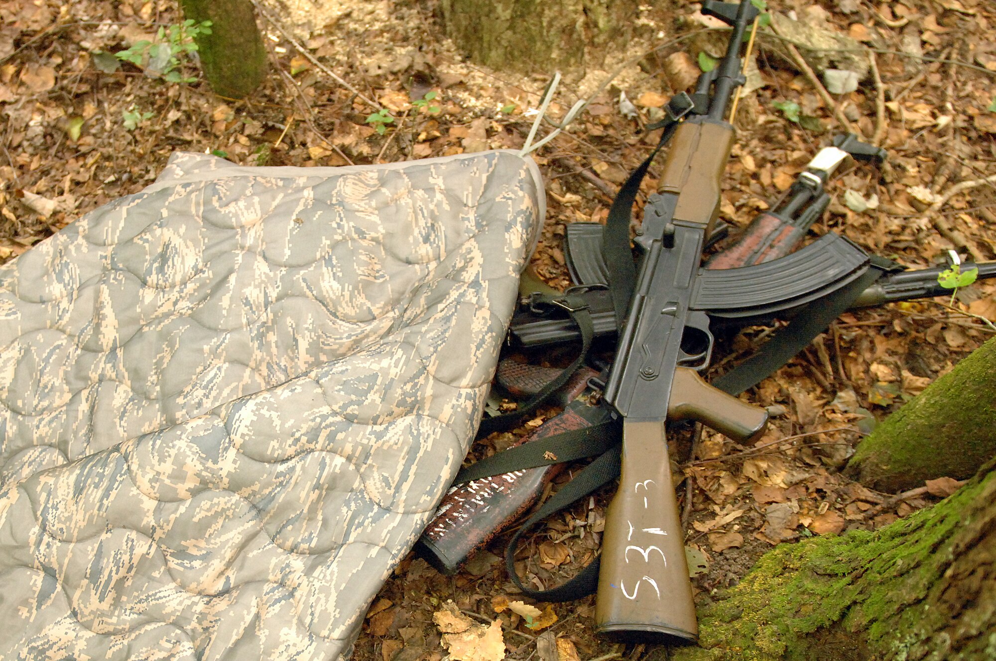 A pile of training weapons lies in the woods during an exercise at Seymour Johnson Air Force Base, N.C., Aug. 25, 2013.  The cache, hidden by a camouflaged blanket and tied to a simulated explosive device, was the target for 4th Security Forces Squadron defenders during a training exercise. (U.S. Air Force photo by Airman 1st Class Brittain Crolley/Released)
