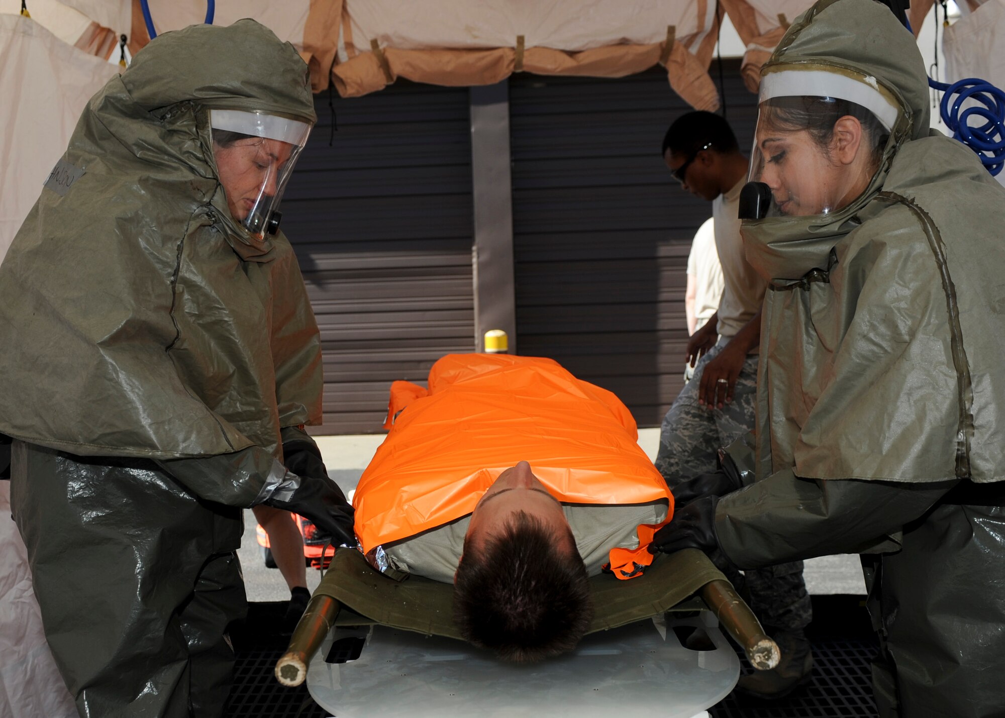 Staff Sgt. Taylor Johnson and Airman 1st Class Leslie Coria, 28th Medical Operations Squadron dental technicians, transport Capt. Cory Peterson, 28th MDOS dentist, along the decontamination line during an in place patient decontamination training exercise at Ellsworth Air Force Base,S.D., Aug. 27, 2013. Training on how to deal with chemical, biological and nuclear decontamination is essential for preparing Air Force medical emergency responders for real-world contingencies. (U.S. Air Force photo by Airman 1st Class Anania Tekurio/Released)