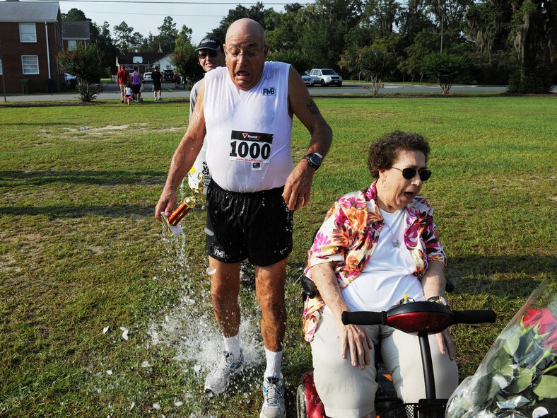 Retired U.S. Air Force Capt. Steve Coyne douses his friend retired Master Sgt. Joe Christian with ice water Aug. 31, 2013, following the Flatlander 5K road race in Lakeland, Ga., while Marlene Christian tries to escape getting wet. The Flatlander was Christian’s 1,000th competitive race and he had many friends and family on hand to help him celebrate.  (U.S. Air Force photo by Master Sgt. Sonny Cohrs/Released)