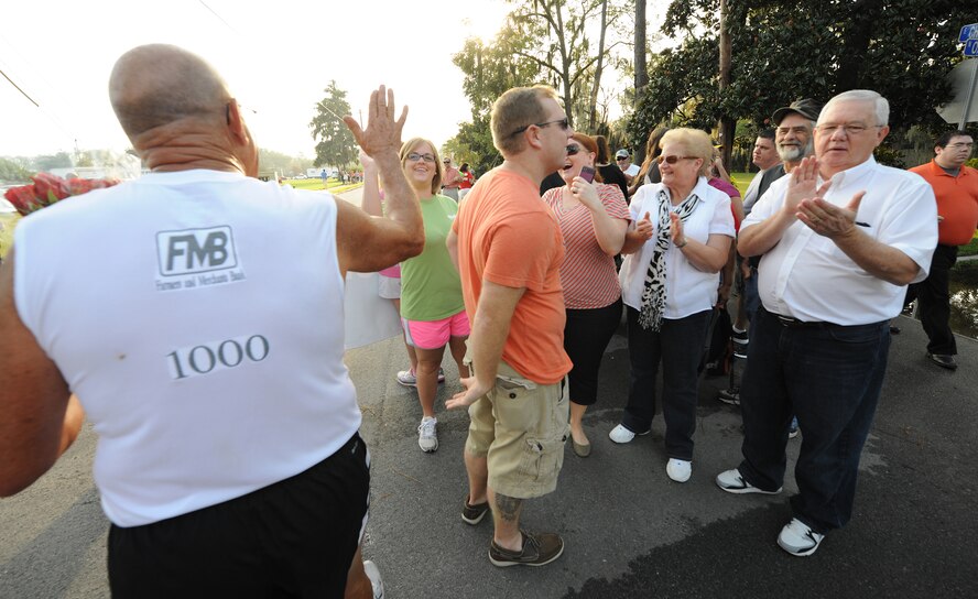 Retired U.S. Air Force Master Sgt. Joe Christian gives high-fives to friends and family after completing the Flatlander 5K road race in Lakeland, Ga., Aug. 31, 2013. Christian runs six days per week and estimates he has run 100,000 miles in the last 35 years. (U.S. Air Force photo by Master Sgt. Sonny Cohrs/Released) 