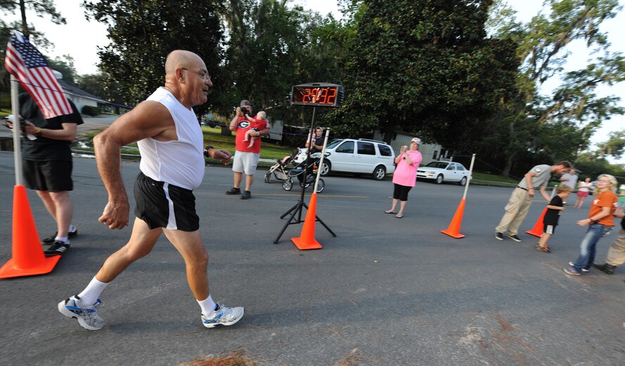 Retired U.S. Air Force Master Sgt. Joe Christian crosses the finish line at the Flatlander 5K Aug. 31, 2013, in Lakeland, Ga., to mark his 1,000th organized race in the last 35 years. Christian began running after he retired from the Air Force and has run nearly every day since he was 40 years old. (U.S. Air Force photo by Master Sgt. Sonny Cohrs/Released) 