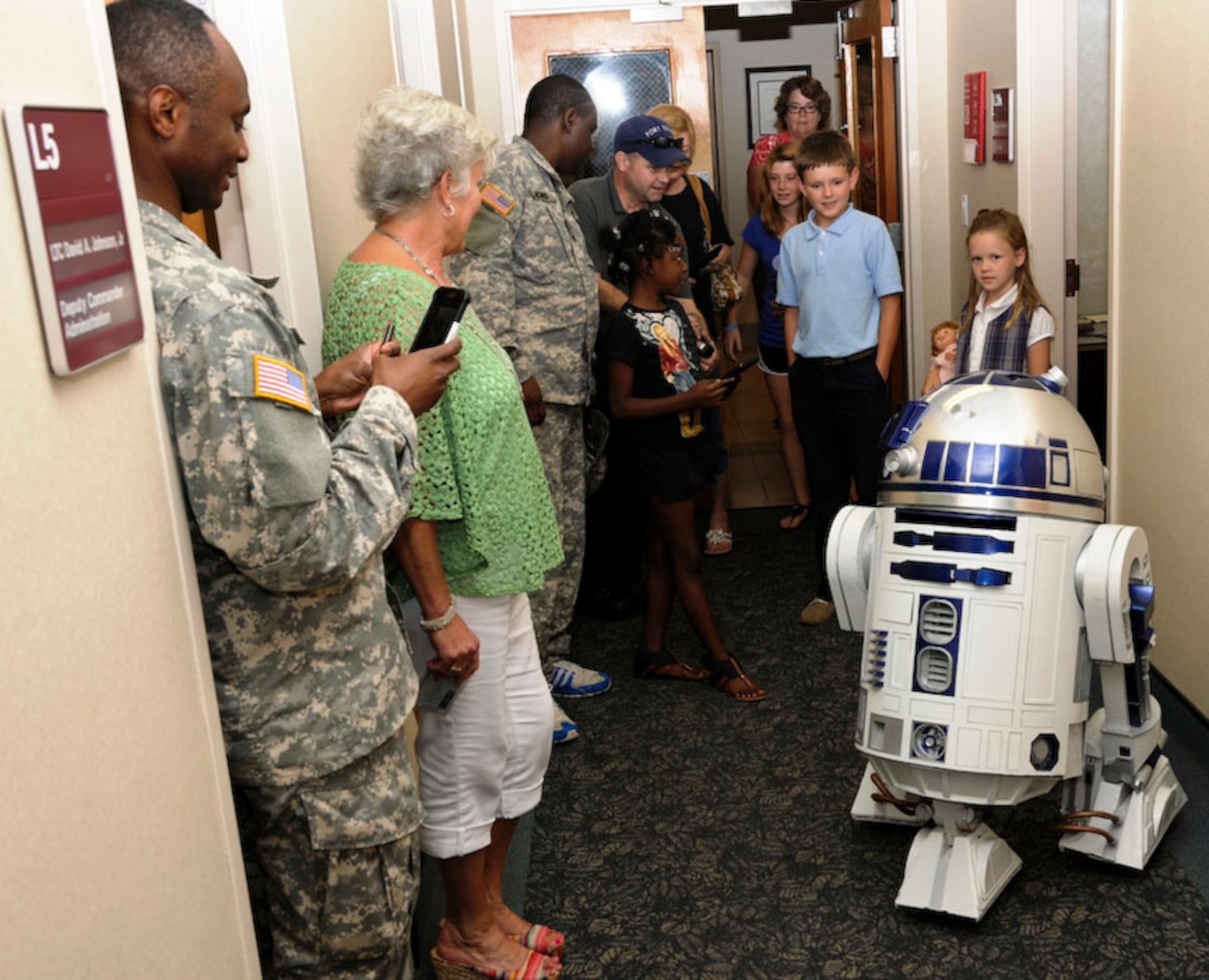 Children and adults alike were drawn into the Star Wars’ universe when this replica of the “R2-D2” astromech droid visited McDonald Army Health Center at Fort Eustis, Va., Aug. 23, 2013. Matt Hammer (left-center, wearing blue cap), an emergency medical technician at the health center, owns and operates the replica robot. (U.S. Army photo by Marlon Martin/Released)