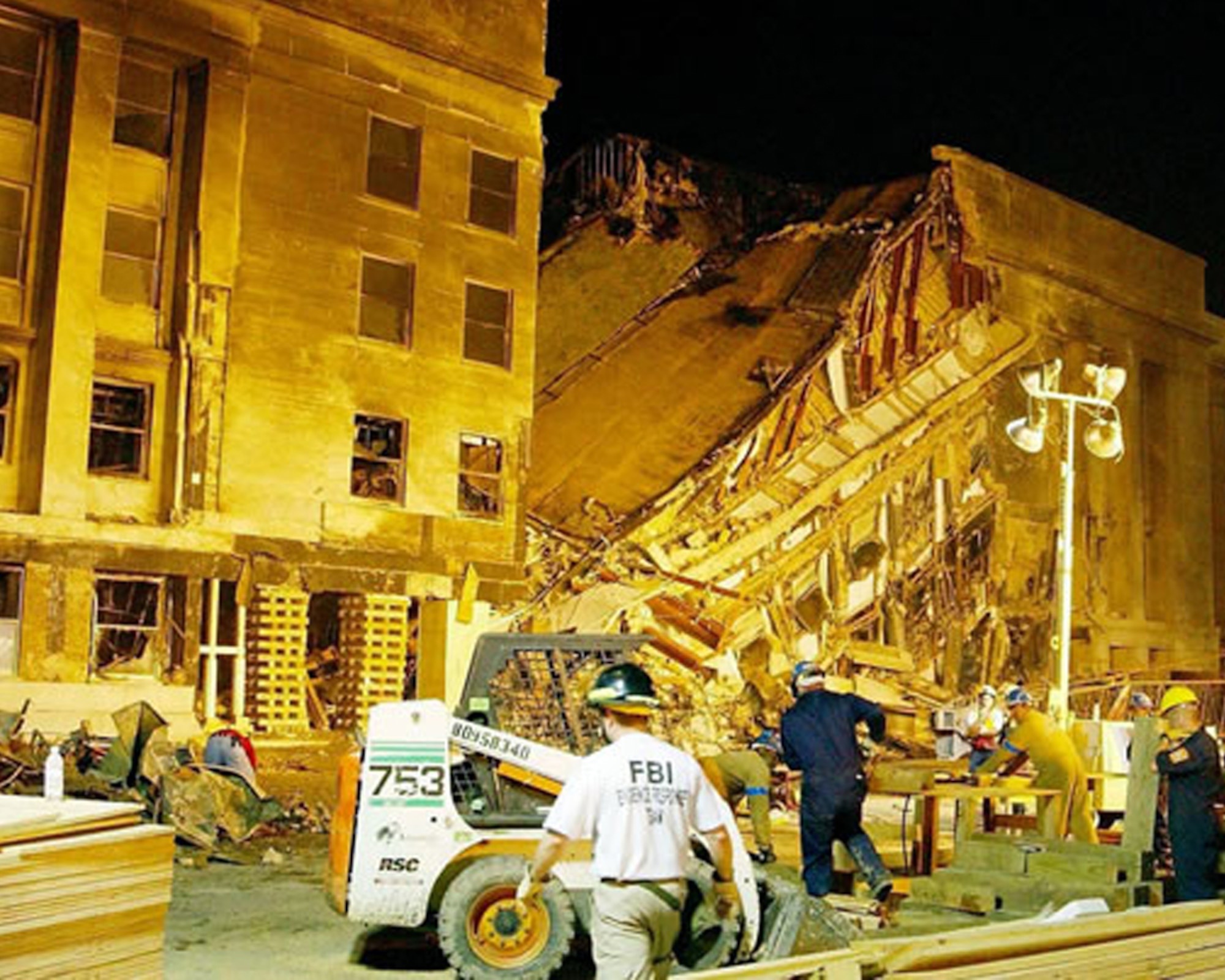 Emergency responders and firefighters work through the night, searching for survivors at the Pentagon, Sept. 11, 2001. The damage was caused when an aircraft, hijacked by al-Qaida terrorists, was deliberately crashed into the side of the building. (Corbis photo by Bill Vaughan/Released)