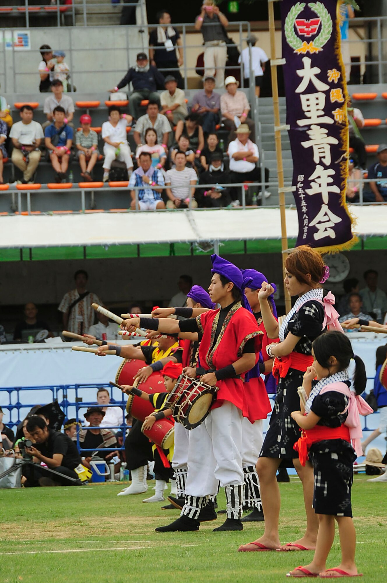 The Taiko drum group performs in a line formation with the Teodori hand dancing team of Ozato Youth Asso during the 58th Okinawa Zento Eisa Festival in Koza Athletic Park Aug. 31, 2013. Eisa dancing is intended to cheerfully send off ancestors during Obon. (U.S. Air Force photo by Staff Sgt. Darnell T. Cannady)