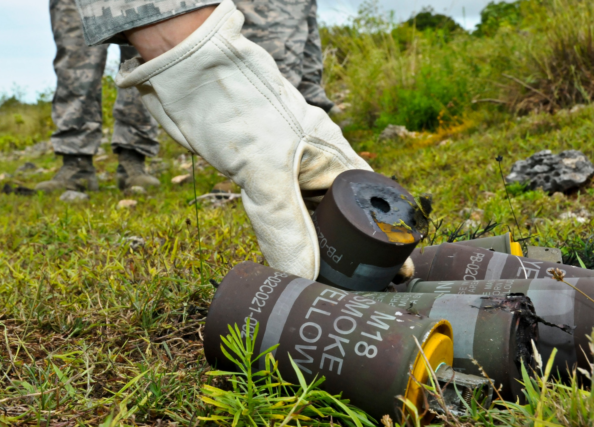 An Airman from the 36th Civil Engineer Squadron Explosive Ordnance Disposal flight piles used smoke grenades after a training exercise, Aug. 26, 2013, on Andersen Air Force Base, Guam. Training with the explosives provides users with necessary knowledge to utilize ground burst simulators and smoke grenades correctly and safely, giving them a sense of reality and comfort before each base exercise. (U.S. Air Force photo by Airman 1st Class Amanda Morris/Released)