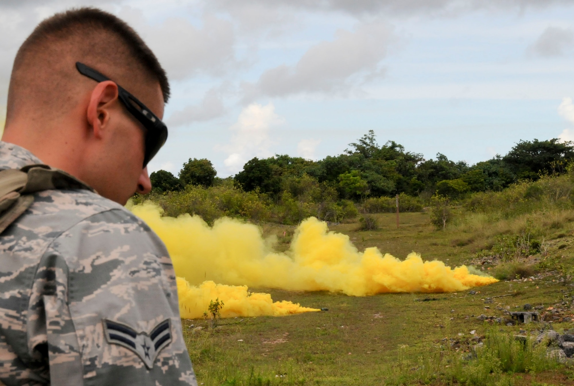 Airman 1st Class Shane Bigham, 36th Civil Engineer Squadron Explosive Ordnance Disposal flight, ensures the field is safe before throwing a smoke grenade, Aug. 26, 2013, on Andersen Air Force Base, Guam. EOD trained Airmen on GBS and smoke grenades to provide a sense of reality during an exercise. (U.S. Air Force photo by Airman 1st Class Amanda Morris/Released)