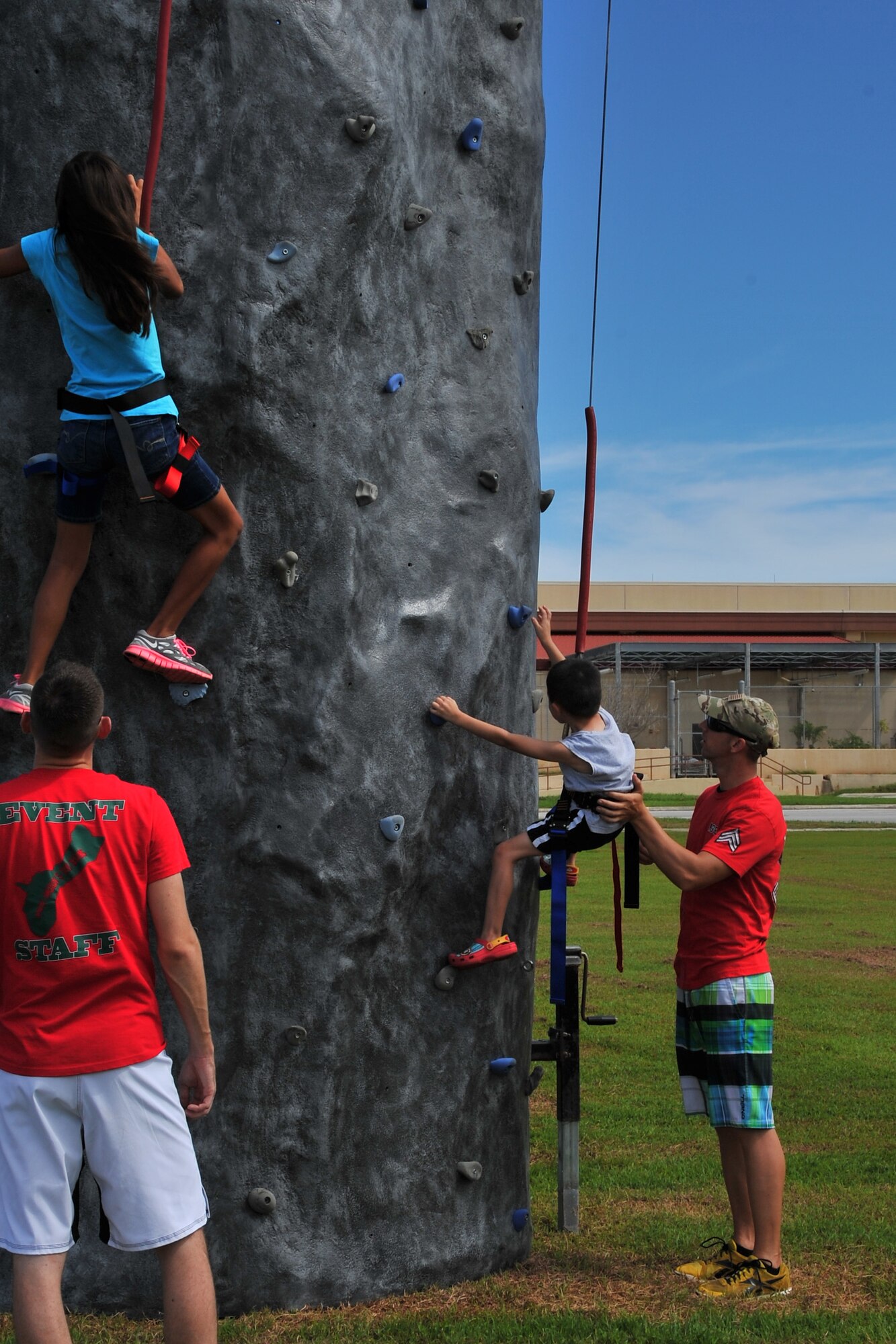Staff Sgt. Jeff Wirgau (left) and Steve Baker (right), both from the 736th Security Forces Squadron, help children climb a rock wall during the Labor Day Bash Aug. 30, 2013, on Andersen Air Force Base, Guam. More than 200 military members and their families attended the event which was held at the Arc Light Memorial Park. (U.S. Air Force photo/Staff Sgt. Melissa B. White/Released)