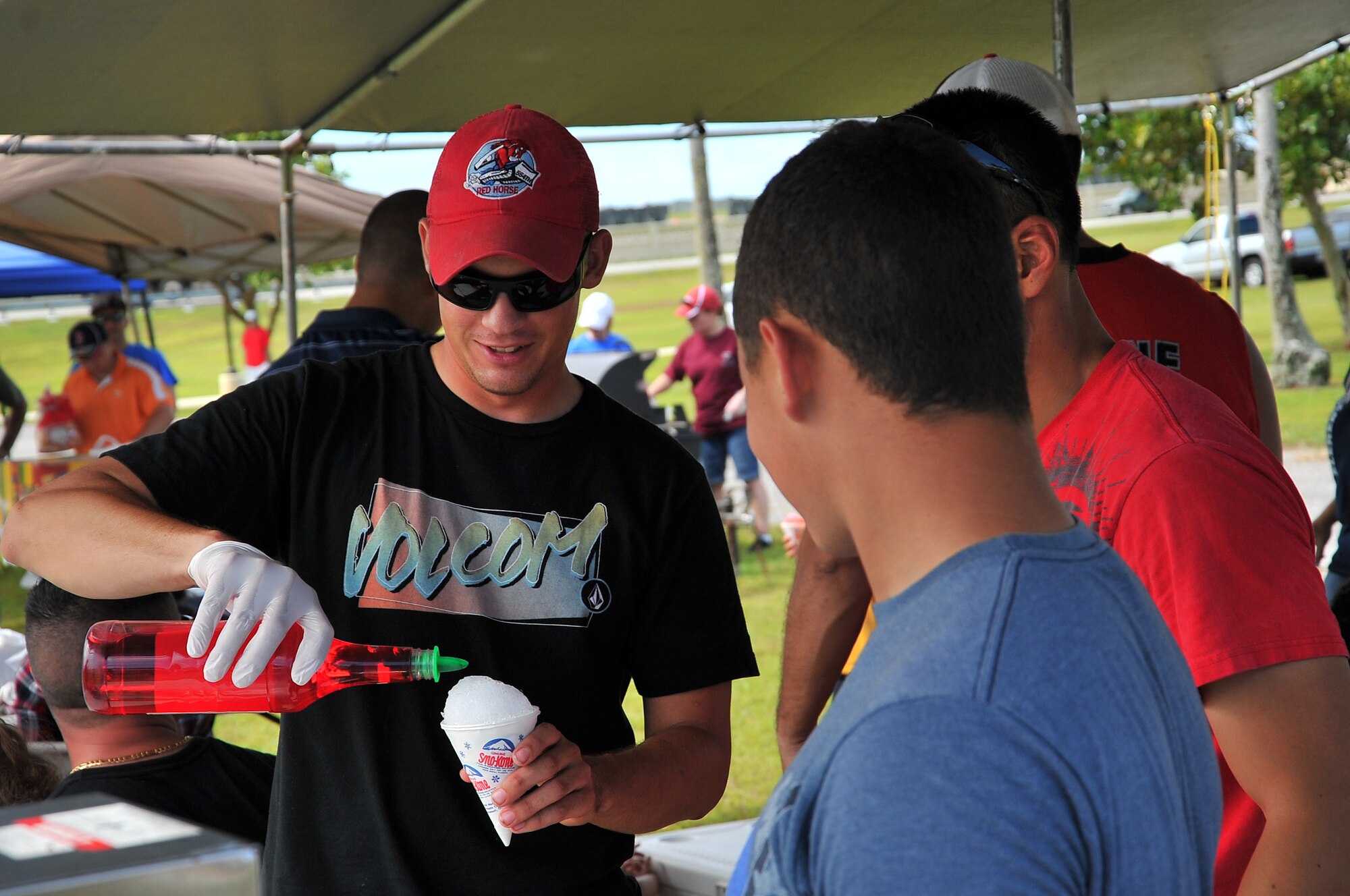 Senior Airman Timothy Bidwell, 554th RED HORSE Squadron, prepares a snow cone for a customer during the Labor Day Bash Aug. 30, 2013, on Andersen Air Force Base, Guam. More than 200 military members and their families attended the event which was held at the Arc Light Memorial Park. (U.S. Air Force photo/Staff Sgt. Melissa B. White/Released)