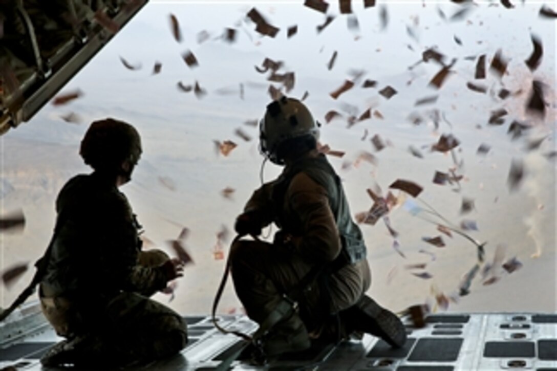 U.S. Army Sgt. Lisa Swan, left, and U.S. Marine Corps Sgt. Joseph Szombathelyi, right, watch leaflets swirl out of a KC-130 Super Hercules over southern Afghanistan on Aug. 28, 2013. The leaflets were dropped in support of operations to defeat insurgency influence in the area.  Swan is a psychological specialist with 303rd Psychological Operations Company and Szombathelyi is a loadmaster with Marine Aerial Refueler Transport Squadron 252. 