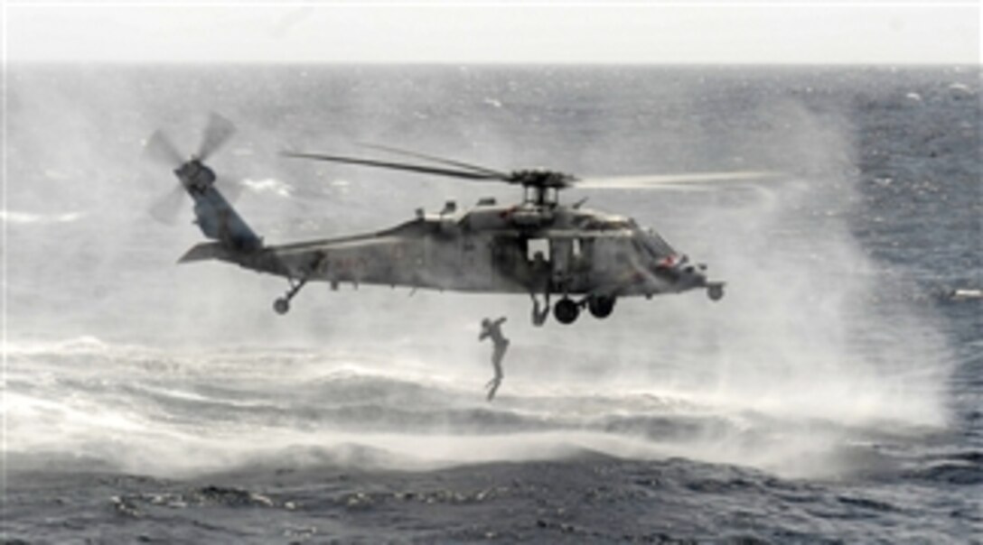 A U.S. Navy explosive ordnance disposalman jumps from an MH-60S Sea Hawk helicopter during a casting and recovery exercise in the Arabian Sea on Aug. 29, 2013.  The disposalman, from Explosive Ordnance Disposal Mobile Unit 11, and the Sea Hawk helicopter assigned to Helicopter Sea Combat Squadron 6, are operating from the flight deck of the aircraft carrier USS Nimitz (CVN 68).  The Nimitz Carrier Strike Group is deployed to the 5th Fleet area of responsibility to conduct maritime security operations and theater security cooperation efforts.  