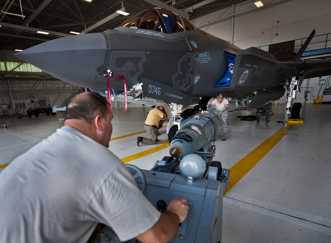 Master Sgt. Karen Griffin and Tech. Sgt. Russ Fontaine maneuver the guided-bomb-unit-31 into position to be loaded onto an F-35A Lightning II Aug. 27, 2013, at Eglin Air Force Base, Fla. This marked the first time Airmen have loaded weapons onto the new joint strike fighter here. Each step and procedure was analyzed to ensure it was correct or needed to be changed. The weapons load procedures perfected by the 33rd Maintenance Group Airmen will be taught to maintenance students in the future. Griffin and Fontaine are assigned to the 33rd Maintenance Group. (U.S. Air Force photo/Samuel King Jr.)