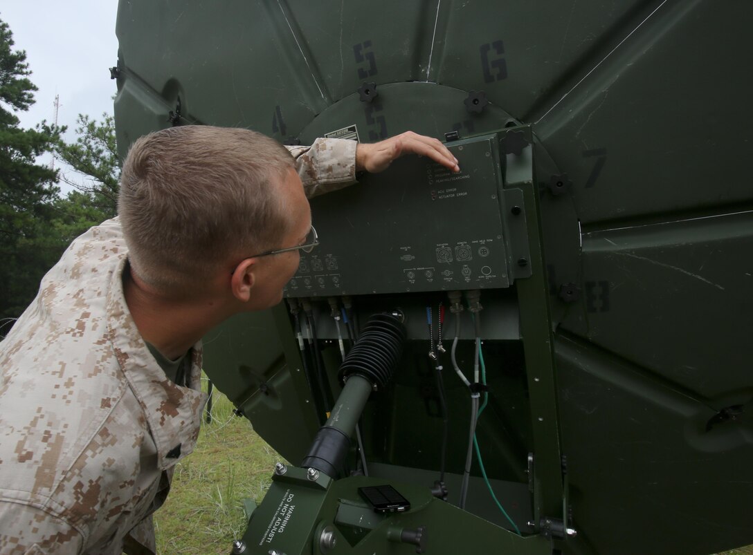 A Marine participating in the 2nd Intelligence Battalion, II Marine Expeditionary Force, Basic Intelligence Training Course, inspects sattelite equipment aboard Marine Corps Base Camp Lejeune, August 14. The equipment helps maintain internet and server access during deployment operations.