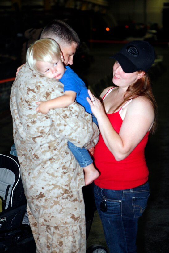 Cpl. Wesley A. Bolin, an embarkation noncommissioned officer in charge with Retrograde and Redeployment in support of Reset and Reconstitution Operations Group, hugs his son and wife before boarding a bus to deploy to Afghanistan, Aug. 29. Bolin is one of 27 Marines and sailors comprising an advance party for R4OG.
