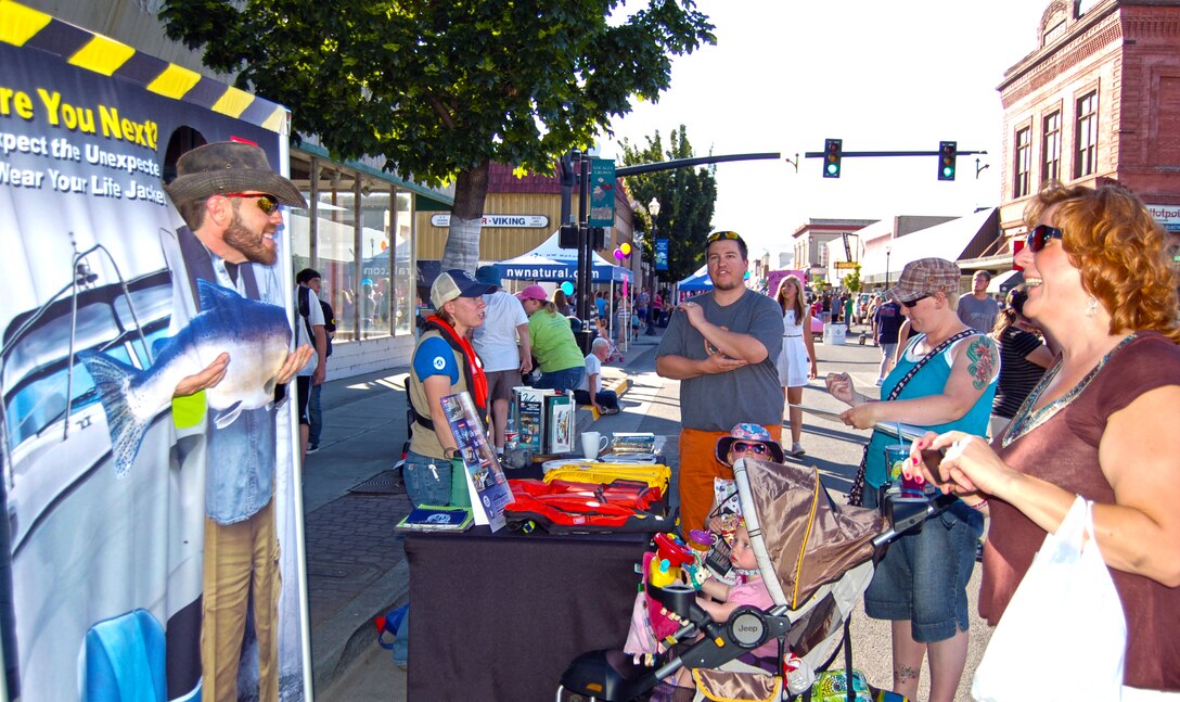 SCA intern Avery Kool is at the Jammin' July Street Fair, in downtown The Dalles, on July 13, 2013. In this photo, she's assisting Park Ranger Amber Tilton in staffing a water safety booth for the U.S. Army Corps of Engineers. A passer-by tries out the photo stand.