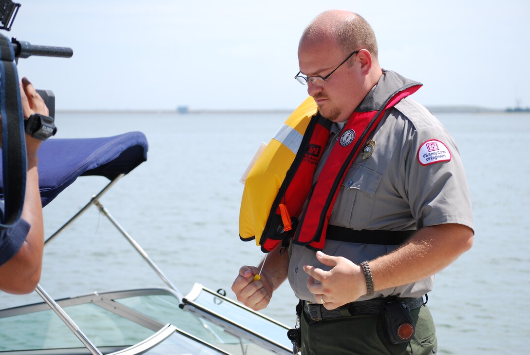 Lewisville Lake park ranger, Jason Owen demonstrates the proper wear and activation of inflatable vest during a Water Safety Media Day.