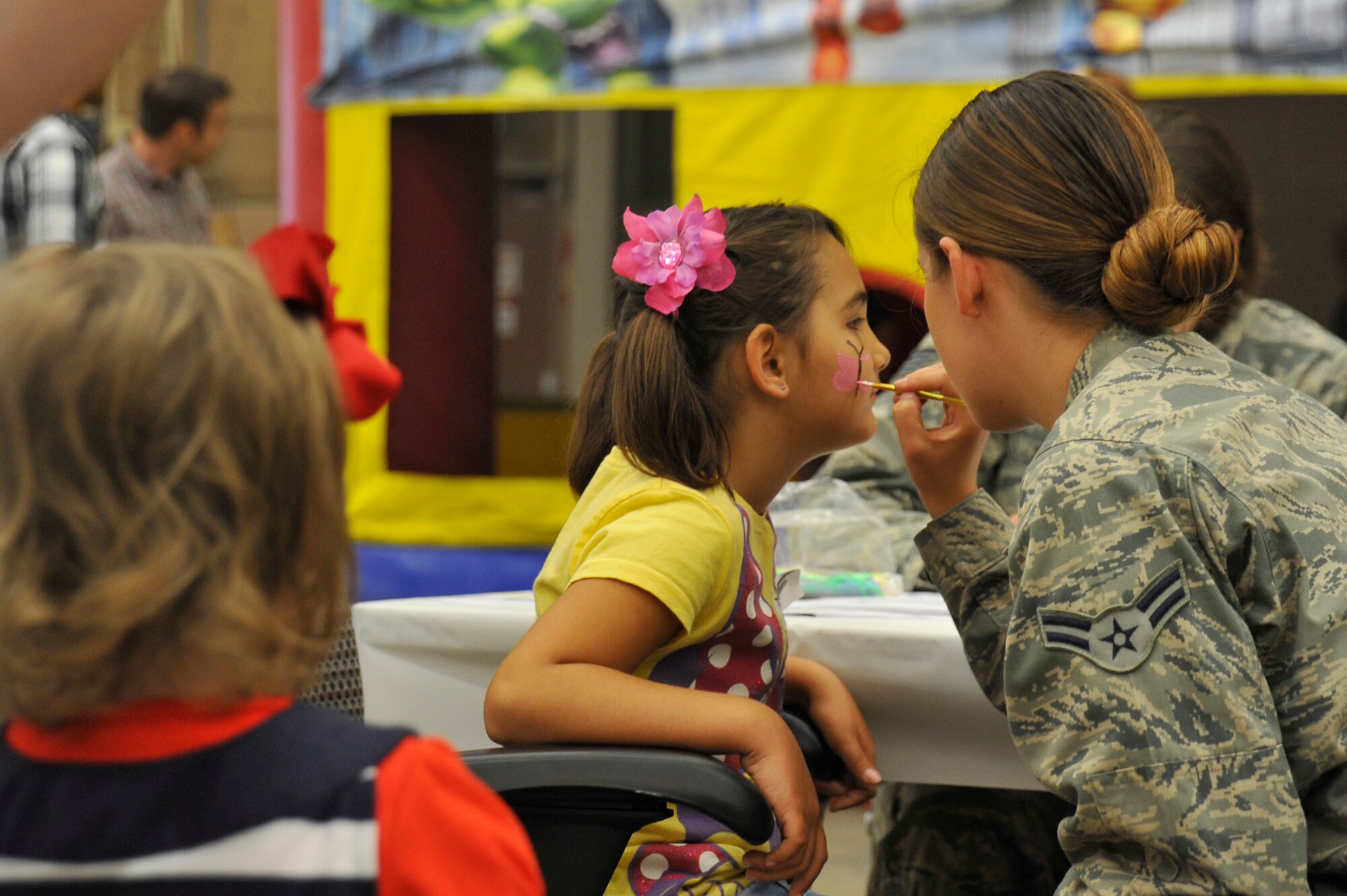 VANDENBERG AIR FORCE BASE, Calif. -- Airman 1st Class Michaela March, 614th Air and Space Operations Center counter space intelligence analyst, assists with the face painting booth during the 614th Air and Space Operations Center's Heritage Day celebration June 14, 2013. The event brought together nearly 400 personnel and family members. (U.S. Air Force photo/Michael Peterson)