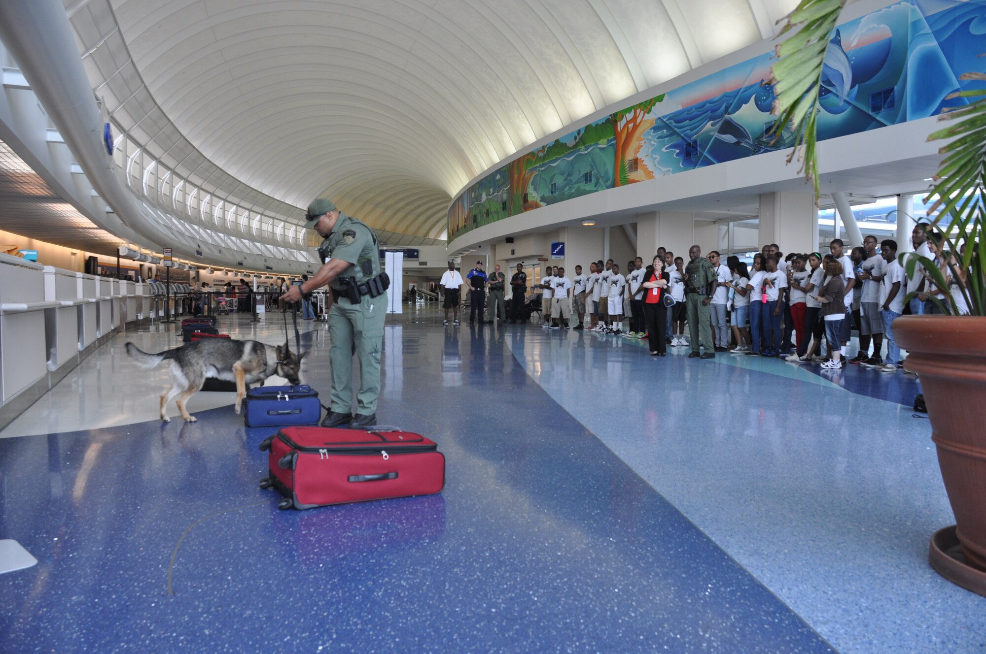 Aviation Career Education Academy students watch as Jay Mitchell, a K-9 police officer with the Jacksonville, Fla., police department and his partner, Leo, demonstrate how they detect explosives at the Jacksonville International Airport, July 24, 2013. The students toured the different jobs at the airport with their volunteer instructors from the 927th Air Refueling Wing. (U.S. Air Force photo by Major Christine Stanaback/Released)