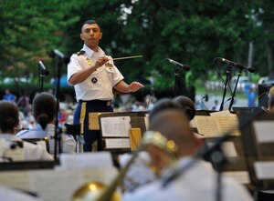 U.S. Army Maj. Leonel Pena, U.S. Army Training and Doctrine Command Band commander, leads the band in a variety of music during the “Music Under the Stars” season finale concert in Magnolia Park at Fort Eustis, Va., Aug. 29, 2013. During the concert, fans were treated to a variety of music, including a special performance by the Williamsburg Fifes and Drums. (U.S. Air Force photo by Staff Sgt. Wesley Farnsworth/Released)