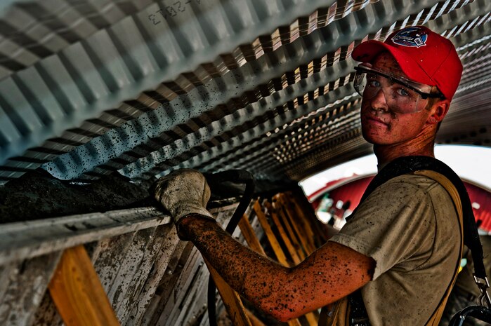 U.S. Air Force Senior Airman Jonathan Jensen, 555th RED HORSE structures journeyman, uses a concrete Hummer Vibrator to disperse wet concrete against the wall of a K-Span building Aug. 29, 2013, at Nellis Air Force Base, Nev. RED HORSE training projects help with base construction efforts while keeping the unit’s Airmen prepared for wartime responsibilities and proficiencies. (U.S. Air Force photo by Senior Airman Daniel Hughes)