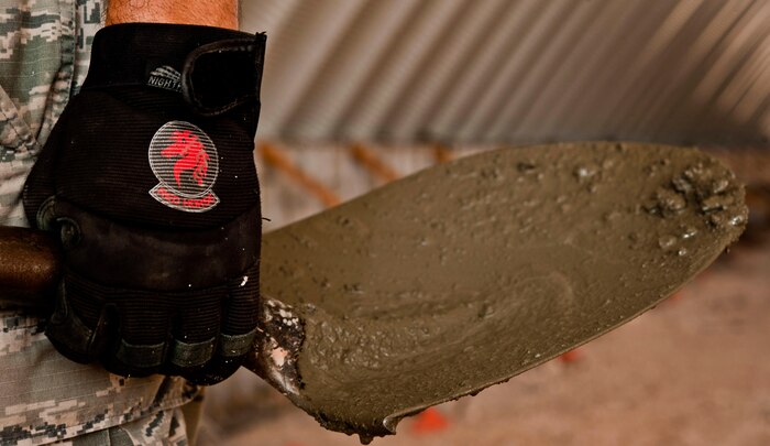An 820th RED HORSE structures Airman, holds his shovel as he waits for the next batch of concrete to be used during the construction of a K-Span building for the 58th Rescue Squadron Aug. 29, 2013, at Nellis Air Force Base, Nev. The squadron provides heavy construction and repair capability to a theater Air Component Commander. (U.S. Air Force photo by Senior Airman Daniel Hughes)