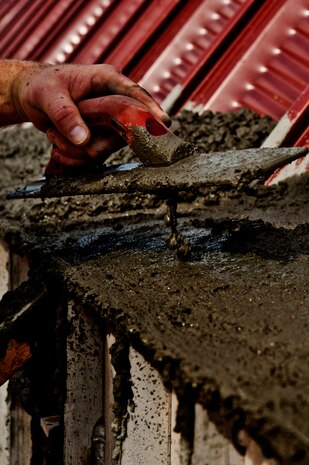 U.S. Air Force Staff Sgt. Aaron Hite, 820th RED HORSE structures craftsman, ensures fresh concrete is flush to the side of a building during the construction of a K-Span building for the 58th Rescue Squadron Aug. 29, 2013, at Nellis Air Force Base, Nev. The Airmen of the 820th RED HORSE are using this construction of this building for training. (U.S. Air Force photo by Senior Airman Daniel Hughes)