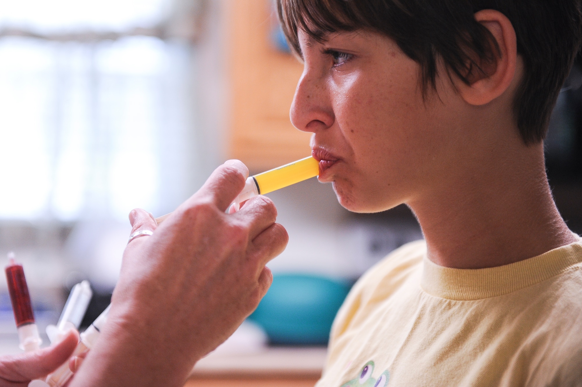 Master Sgt. Beth Jungk, a 19th Communications Squadron plans and programs manager, gives her daughter Morgan medicine Aug. 24, 2013, at their home in Jacksonville, Ark. Because of her disabilities, Morgan takes several syringes full of medicine every morning. (U.S. Air Force photo by Staff Sgt. Jake Barreiro)