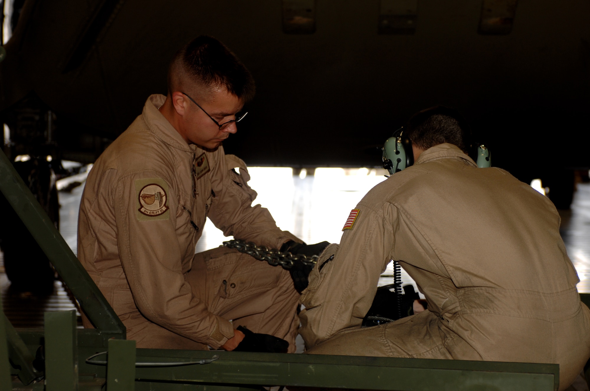 Senior Airman Jacob Risch (left) and Airman 1st Class Colt Weins (right), both 9th Airlift Squadron loadmasters from Dover Air Force Base, Del., connect a Chinook helicopter to a hoist for offloading at Kandahar Airfield, Afghanistan Aug. 24, 2013. The C-5M Super Galaxy was used as part of a multi-modal mission to move more than 120 helicopters during the rotation of the 3rd Combat Aviation Brigade to the 1st CAB here. (U.S. Air Force photo by Senior Airman Jack Sanders)