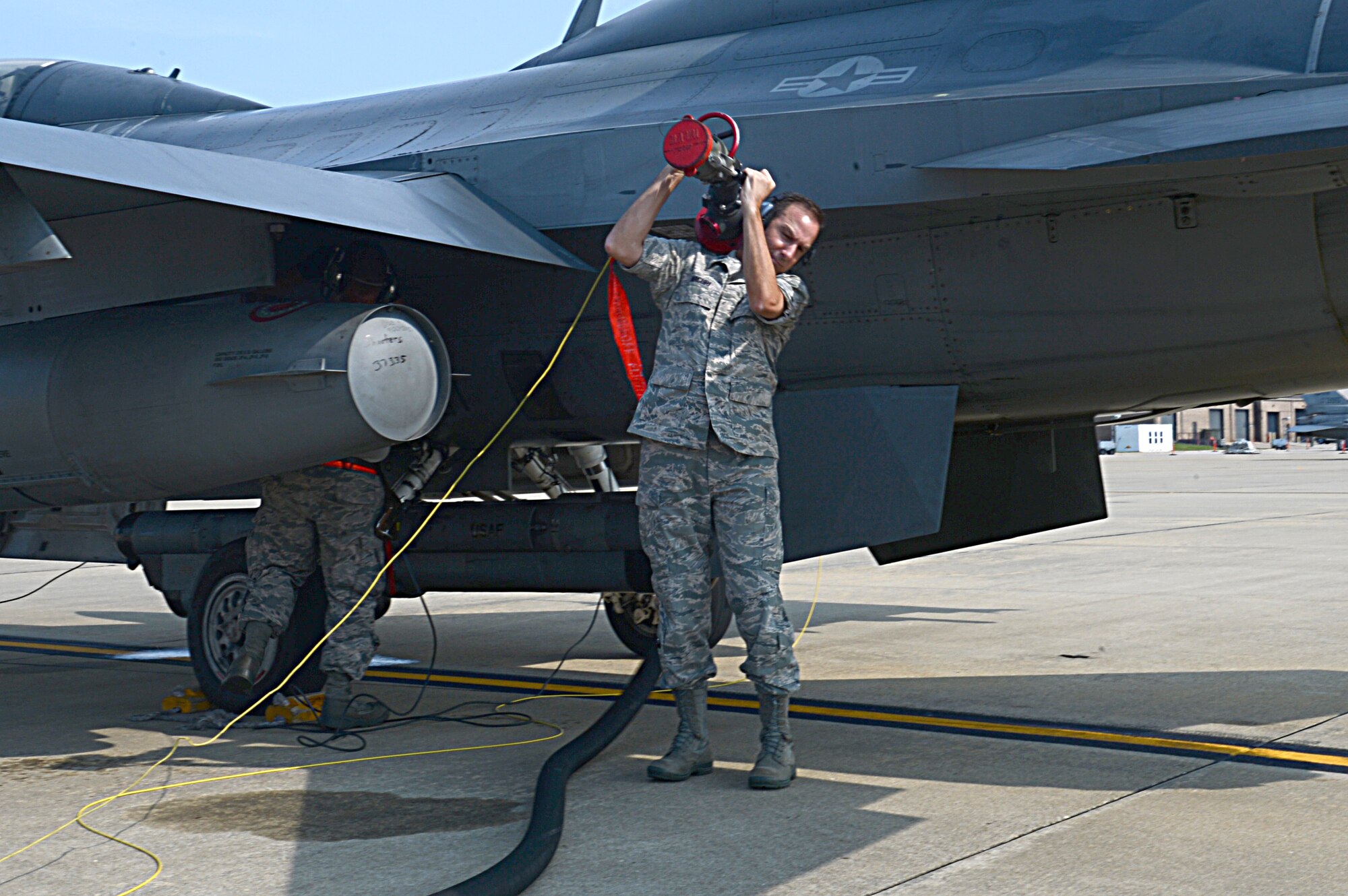 Hoisting a fuel hose over his shoulder, U.S. Air Force Col. Scott Arcuri, 20th Mission Support Group commander, assists in the hot pits refueling of an F-16 Fighting Falcon at Shaw Air Force Base, S.C., Aug. 28, 2013.  Hot pits refueling is a process used to refuel the aircraft without having to turn its engines off. He personally refueled two home station F-16 aircraft with 2,447 gallons of Jet-A fuel.(U.S. Air Force photo by Airman 1st Class Jonathan Bass/Released)