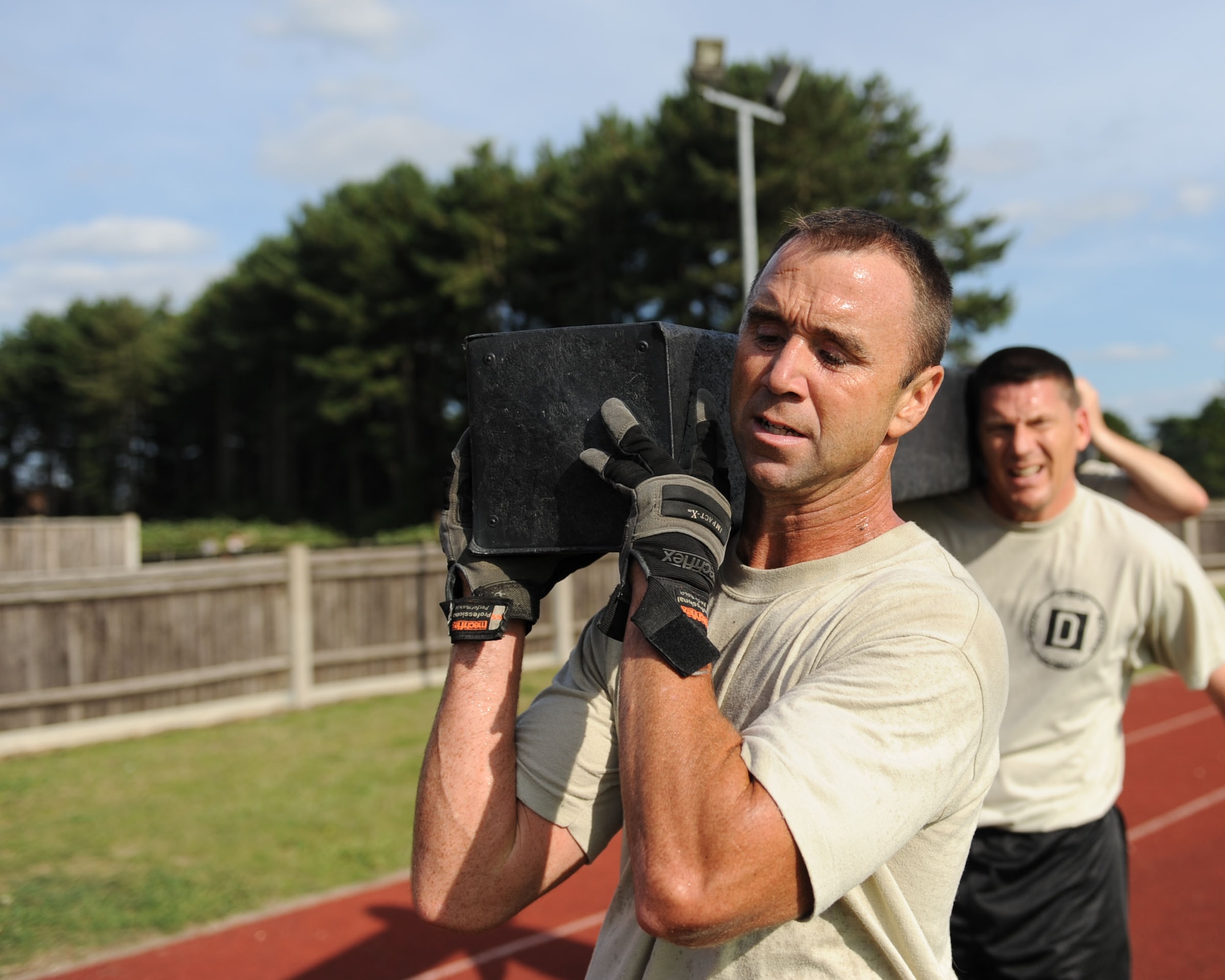 U.S. Air Force Chief Master Sgt. Scott Knupp, left, 100th Civil Engineer Squadron fire chief, and U.S. Air Force Chief Master Sgt. Tracy Jones, 100th Air Refueling Wing command chief, carry an 8-foot, 200-pound section of dunnage Aug. 29, 2013, during the Chiefs vs. Eagles Monster Mash at Heritage Park on RAF Mildenhall, England. Base leadership overcame several challenges including a jerry can carry, an all-terrain vehicle pull and a forklift-tire flip. The monster mash encouraged base leadership to work together and promoted teamwork, leadership and followership. (U.S. Air Force photo by Airman 1st Class Preston Webb/Released)