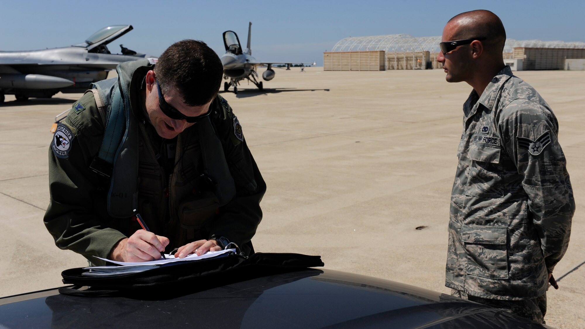 KUNSAN AIR BASE, Republic of Korea -- Colonel S. Clinton Hinote, 8th Fighter Wing commander, reviews flight documents with Senior Airman Alex Lenz, 8th Aircraft Maintenance Squadron crew chief, Aug. 14, 2013. Hinote flew in a partnership flight designed to practice aerial maneuvers and teamwork.  (U.S. Air Force photo by Senior Airman Armando A. Schwier-Morales/ Released)