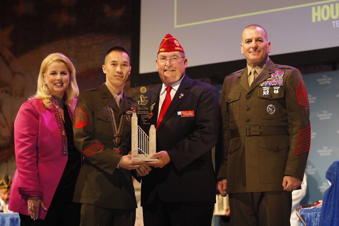 Sergeant Man Chan accepts the American Legion's Spirit of Service Award from the national commander of the American Legion, James E. Koutz, the senior enlisted advisor to the Chairman of the Joint Chiefs of Staff, Marine Sgt. Maj. Bryan B. Battaglia., and reporter Rita Cosby in Houston, Aug. 27, 2013. Chan, the substance abuse control officer with 2nd Supply Battalion, Combat Logistics Regiment 25, 2nd Marine Logistics Group, received the award for 465 hours of volunteer work while serving in a challenging billet. (Official Marine Corps Photo by Sgt. B. A. Curtis)