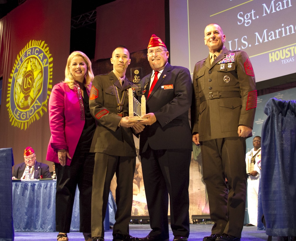 Sergeant Man Chan accepts the American Legion's Spirit of Service Award from the national commander of the American Legion, James E. Koutz, the senior enlisted advisor to the Chairman of the Joint Chiefs of Staff, Marine Sgt. Maj. Bryan B. Battaglia., and reporter Rita Cosby in Houston, Aug. 27, 2013. Chan, the substance abuse control officer with 2nd Supply Battalion, Combat Logistics Regiment 25, 2nd Marine Logistics Group, received the award for 465 hours of volunteer work while serving in a challenging billet. (Official Marine Corps Photo by Sgt. B. A. Curtis)