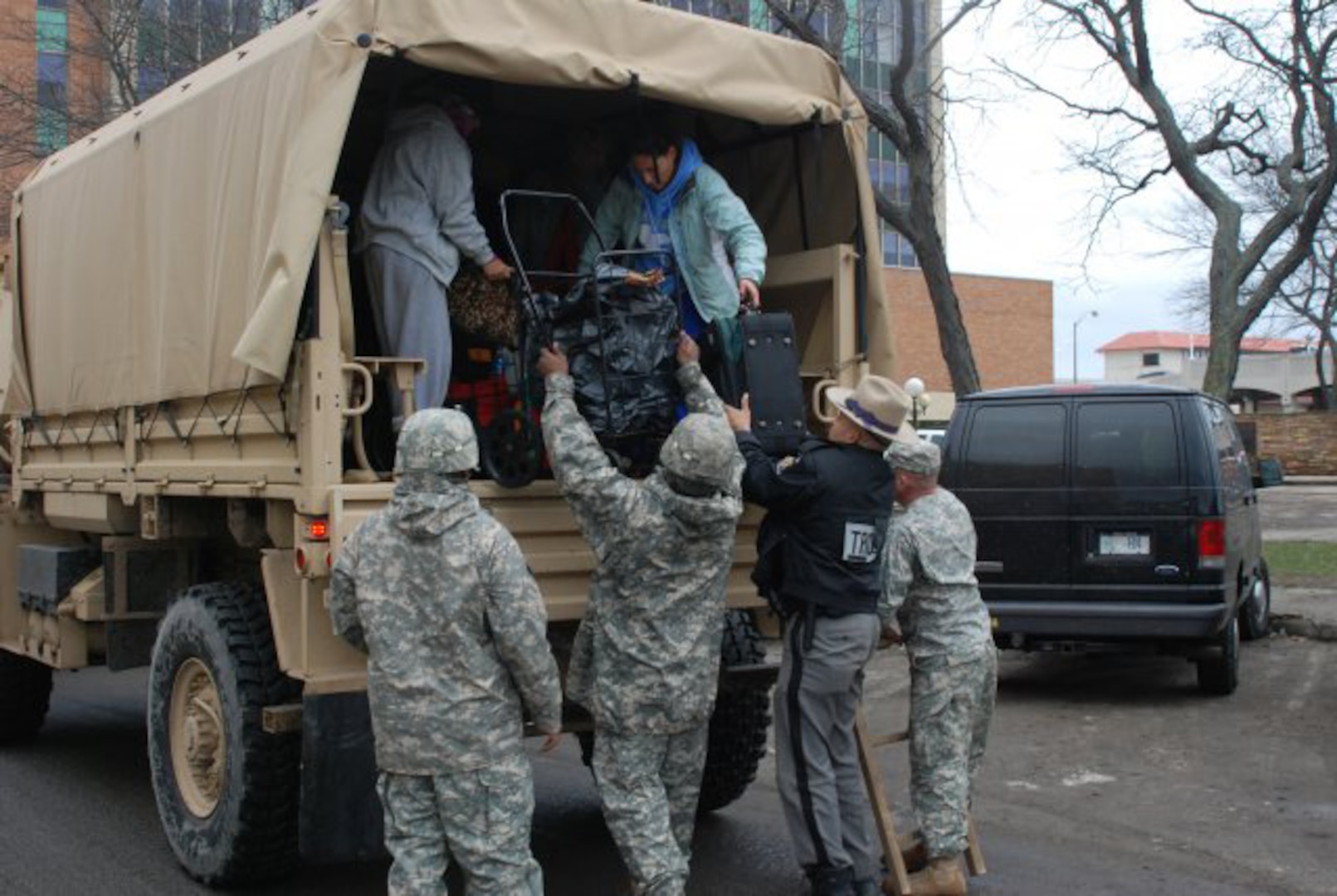 New York Army National Guard Soldiers from Company F, 427th Brigade Support Battalion, along with New York State Troopers, help residents arriving at Long Beach City Hall in Long Beach, N.Y., for evacuation to shelters.