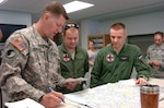 Estonian air force Capts. Rene Kallis, right, and Martin Noorsalu, middle, go over a flight plan with a Maryland Army National Guard member at Weide Army Airfield in Edgewood, Md. After training with the Maryland Army Guard for a year as part of the State Partnership Program, the Estonian pilots are scheduled deploy to Afghanistan where they will serve with the Maryland Army Guard's C Company, 1st Battalion, 169th Aviation Regiment, a medical evacuation unit that deployed to Afghanistan earlier this year.