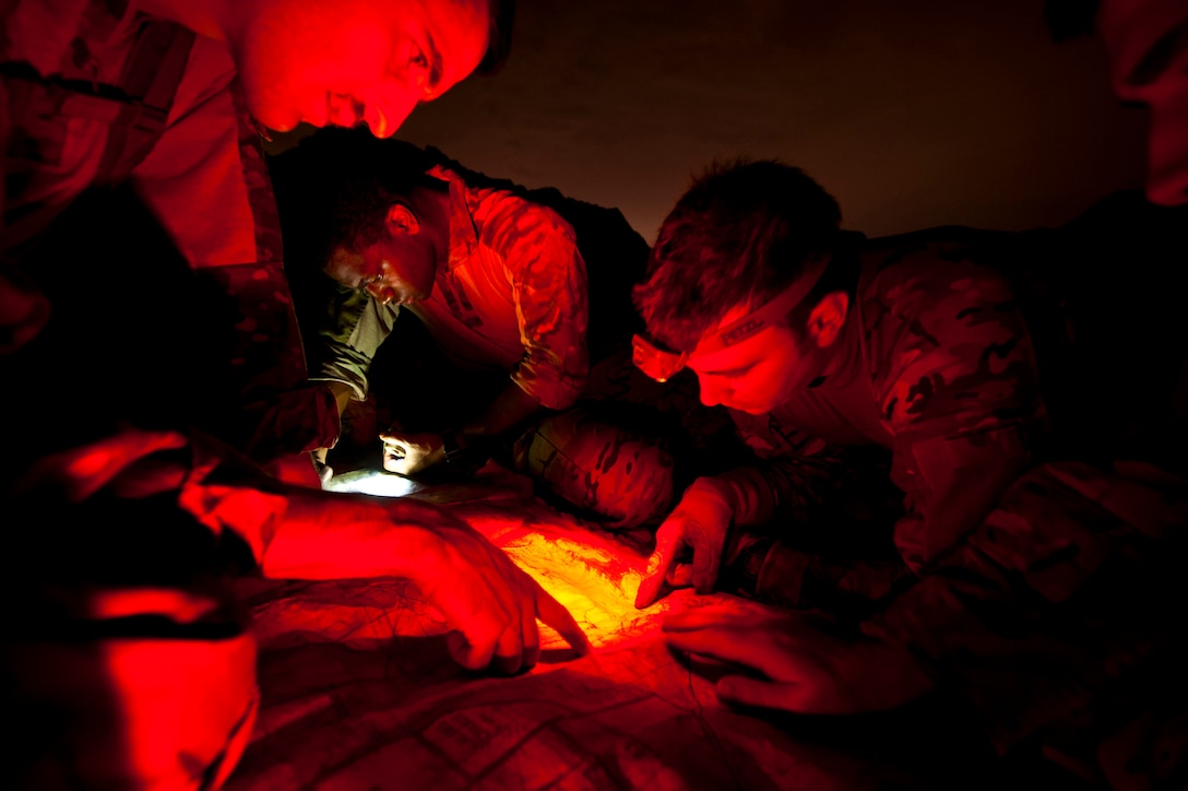 Capt. Bret Cove and Capt. Alex Sira (foreground) establish coordinates on a map while Staff Sgt. Chris Myers  records information during a survival, evasion, resistance and escape familiarization training Aug. 23, 2013, at Nellis Air Force Base, Nev. SERE specialists teach students how to adapt to all environments and their associated weather conditions. Cove and Sira are 66th Rescue Squadron HH-60 Pave Hawk pilots and Myers is a 66th RQS special missions aviator. (U.S. Air Force photo/Senior Airman Brett Clashman)