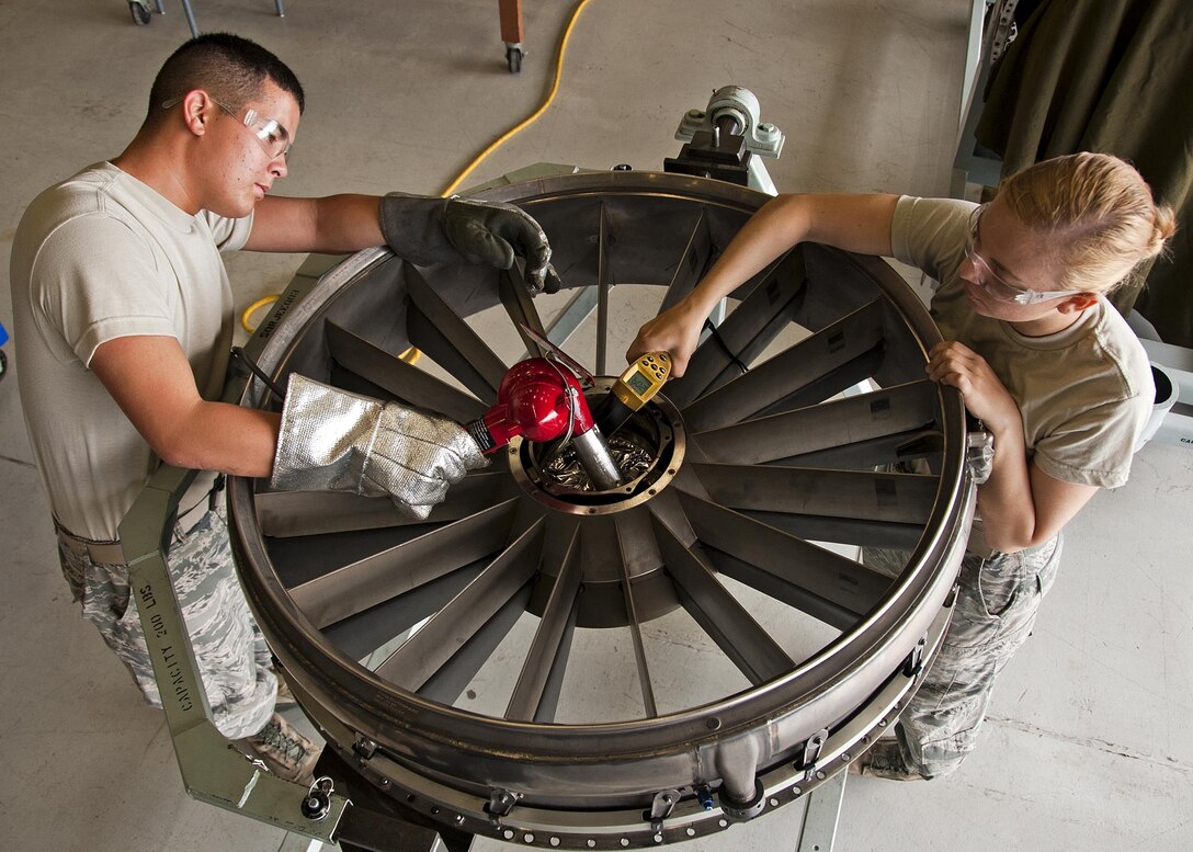 Airmen Brandinn Kim and Elizabeth Ulring heat a No.1 bearing housing on the F-110 engine before installing a rotating air seal Aug. 27, 2013, at Sheppard Air Force Base, Texas. The engine is from an F-15 Eagle. Kim and Ulring are assigned to the 361st Training Squadron Jet Propulsion course. (U.S. Air Force photo/Frank Carter)