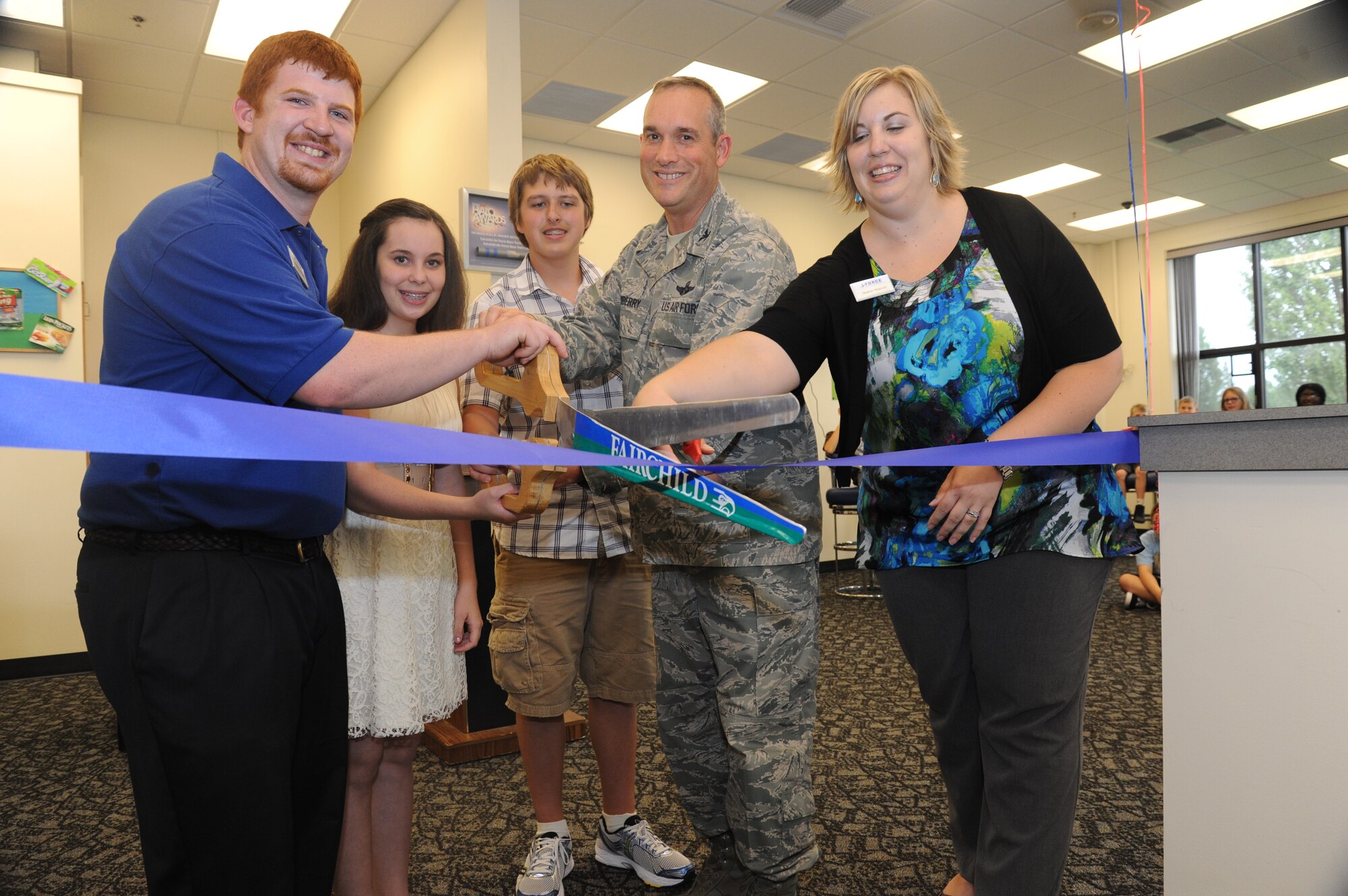 Col. Brian Newberry, 92nd Air Refueling Wing commander, joins staff members in cutting the ribbon to commemorate the reopening of the Teen Center at Fairchild Air Force Base, Wash., Sept. 4, 2013.  The Teen Center, which gives Fairchild teenagers recreational opportunities, began its fall hours for the new school year.  (U.S. Air Force photo by Airman 1st Class Sam Fogleman/Released)