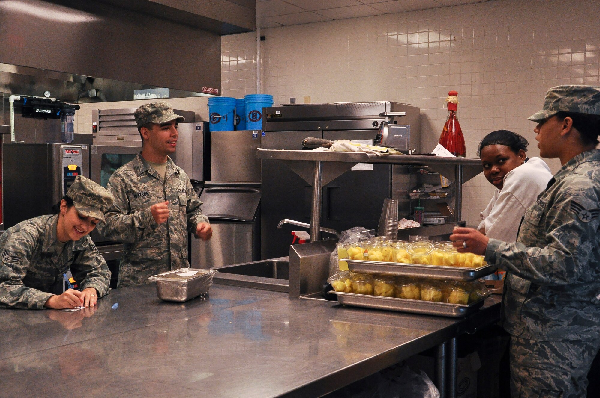 Airmen and a Aramark food service employee from the 19th Force Support Squadron hold a conversation before finishing final preparations for lunch Aug. 21, 2013, at Little Rock Air Force Base, Ark. The dining facility hours are Monday through Sunday from 6:30 a.m. to 6:30 p.m. (U.S. Air Force photo by Senior Airman Regina Agoha) 