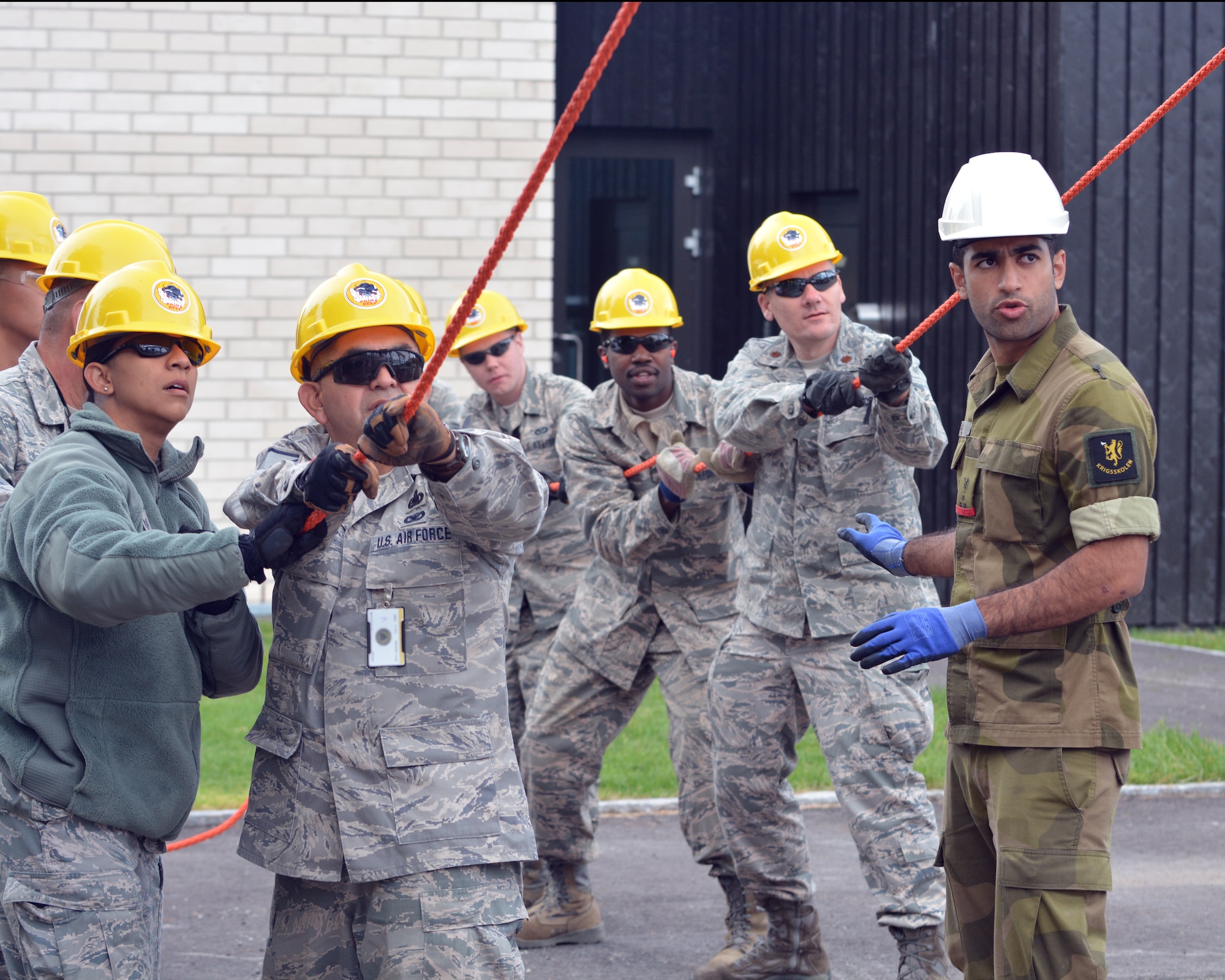 U.S. Air Force Staff Sgt. Liza McClaren (left) assists members of the 149th Civil Engineering Squadron, a subordinate unit of the Texas Air National Guard’s 149th Fighter Wing, headquartered at Joint Base San Antonio – Lackland, Texas, assemble a steel-frame structure at the Norwegian Military Academy (Krigsskolen), at Camp Linderud, in Oslo, Norway, Aug. 13, 2013. McClaren, a financial program manager with the 149th Fighter Wing, was in Norway with the 149th Civil Engineering Squadron as part of the National Guard Bureau’s deployment for training program. Also included in the photo is Cadet Aqeel Ahmed, the project manager. (This image was modified to obscure personally identifiable information on one of the subject's identification badge for security and privacy reasons.) (U.S. Air National Guard photo by Staff Sgt. Phil Fountain / Released)