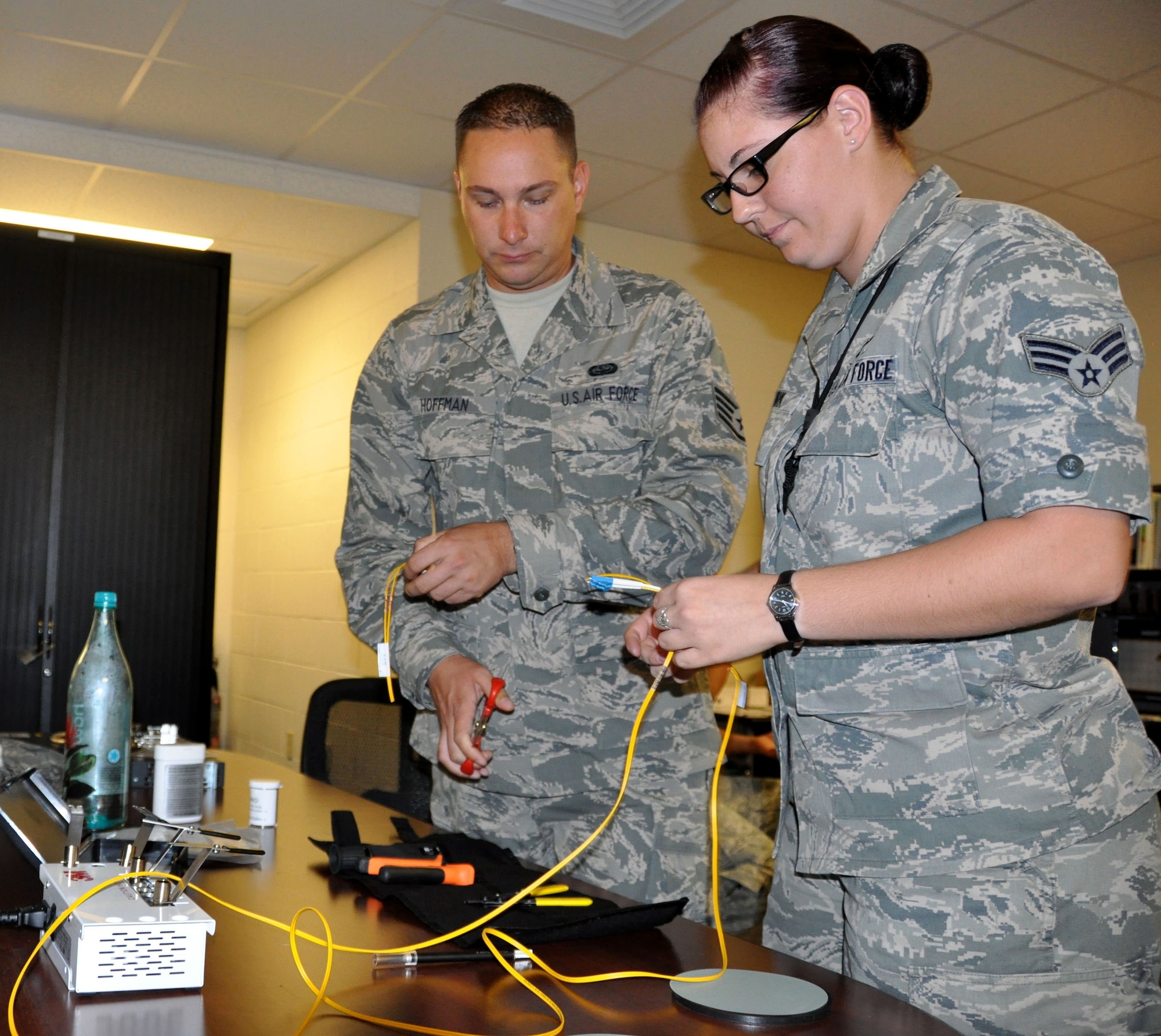 Staff Sgt. Jason Hoffman, 50 IS, and SrA Diandraleigh Burk, 792 ISS, train with fiber optic cables at Joint Base Pearl Harbor-Hickam, Hawaii. The fiber optic termination training provided by Hoffman will save money while making the 792 ISS infrastructure more secure. (U.S. Air Force Photo/Capt. Joe Simms)