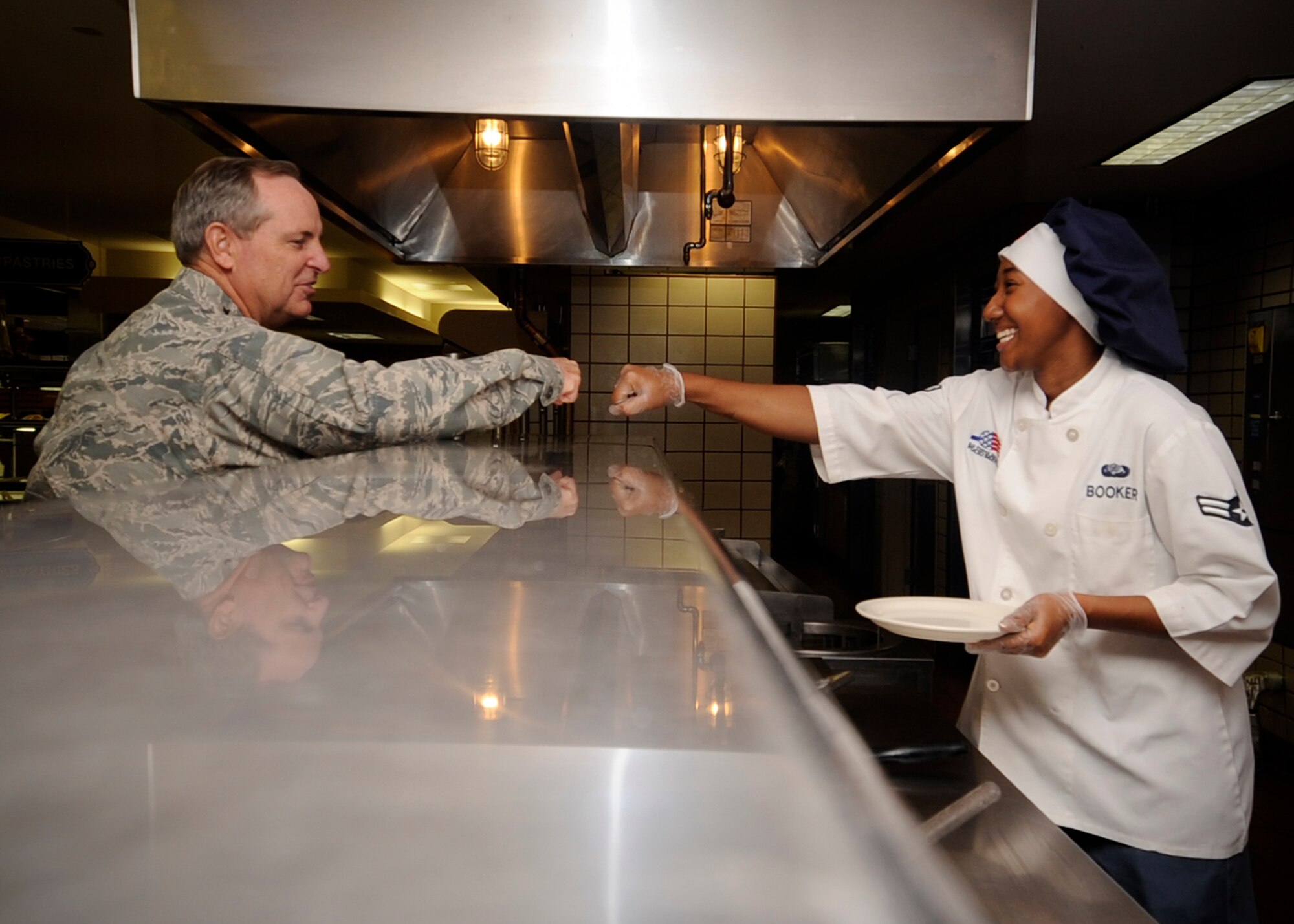 Air Force Chief of Staff Gen. Mark A. Welsh III fist bumps Airman 1st Class Carissa Booker while preparing for lunch Aug. 30, 2013, during a visit to Eielson Air Force Base, Alaska. Welsh, his wife, Betty, and Athena Cody, wife of Chief Master Sgt. of the Air Force James Cody, visited the base to discuss opportunities and challenges in the region and thank Airmen and their families for their dedication and sacrifice. Eielson was the final stop on their two-week tour of the Pacific region. Booker is a food services journeyman assigned to the 354th Force Support Squadron at Eielson. (U.S. Air Force photo by Senior Airman Shawn Nickel/Released)